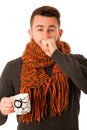 Man with flu and fever wrapped in scarf holding cup of healing t