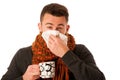 Man with flu and fever wrapped in scarf holding cup of healing t