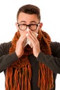 Man with flu and fever wrapped in scarf sneezing into handkerchief.