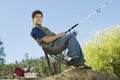 Man fly fishing, sitting on collapsible chair