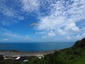 A man flying in the beautiful blue cloudy beautiful sky withe the sea and the mountain background, parachute with a motor, paramot Royalty Free Stock Photo