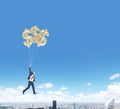 Man flying with dollar balloons over city