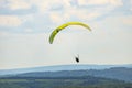 A man flying a green paraglider over a forest on a cloudy day. Royalty Free Stock Photo