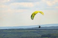 A man flying a green paraglider over a forest on a cloudy day. Royalty Free Stock Photo