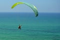 Man is flying on green paraglider in the sky above the azure sea. Balance, extreme sports, lifestyle. Mediterranean Sea Israel