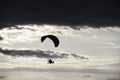 Man flying a paraglider against the clouds