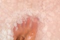 Man foot fingers in salt flakes in pink water, spa