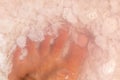 Man foot fingers in salt flakes in pink water, spa