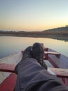 Man foot on traditional wood boat at calm lake with dramatic sunrise colorful sky reflection Royalty Free Stock Photo