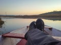 Man foot on traditional wood boat at calm lake with dramatic sunrise colorful sky reflection Royalty Free Stock Photo