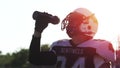 A man in an football suit at sunset drinks water in a slow-motion shot
