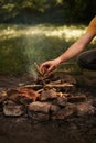 A man in the forest kindles a fire. man throws branches into the fire close-up Royalty Free Stock Photo