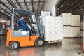 A man on a forklift works in a large warehouse, unloads bags of raw materials