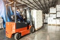 A man on a forklift works in a large warehouse, unloads bags of raw materials Royalty Free Stock Photo