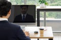 A man in formal attire participate in a video conference from his workspace. A computer screen reflect his image while he focus on Royalty Free Stock Photo