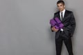 A man in a formal suit with a tie holds a box with a gift. Isolated on grey. Holiday concept Royalty Free Stock Photo