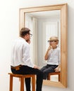 Man in formal wear sitting and looking in mirror with reflection of him being a child. Dreams and reality. Conceptual Royalty Free Stock Photo