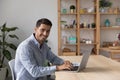 Man freelancer sit at desk with laptop staring at camera