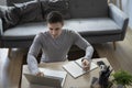 Man freelancer sitting on floor in living room and working with computer laptop. Royalty Free Stock Photo