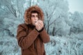 Man freezes in the cold in the forest and tries to wipe his hands with his breath. The concept of frostbite of the extremities Royalty Free Stock Photo