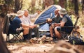 Man, friends and camping in nature with coffee for travel, adventure or summer getaway together on chairs in forest Royalty Free Stock Photo