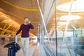 Man front walking at the airport using mobile phone