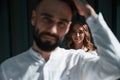 Man is in front of woman. Beautiful young couple is standing together against dark green background Royalty Free Stock Photo