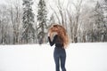 Man is in front of woman. Rear view of girl with long hair runs near the forest to the automobile in wintertime Royalty Free Stock Photo