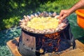 Man frying chicken wings and potatoes at barbecue grill disc wok at backyard bbq party Royalty Free Stock Photo