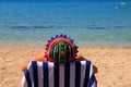 A man in a funny panama sits in a deck chair on a ecological beach under the Blue Flag in Croatia. Summer sea vacation near clean