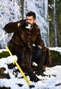 Man in fur coat drinks from metal flask. Brutal gamekeeper.