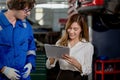 Man garage worker and woman customer talking to discuss the details of car repairs. male mechanic holding clipboard and writes Royalty Free Stock Photo