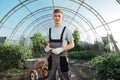 Man with garden tools.Young happy farmer posing with abrasive tools in a greenhouse Royalty Free Stock Photo