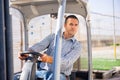 Man gardener driving agricultural vehicle in hothouse