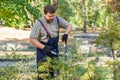 Man gardener in protective gloves with garden shears, scissors or secateurs cutting a thuja or juniper topiary hedge in public Royalty Free Stock Photo
