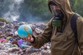 A man in a gas mask looks at when the beautiful planet earth. On the background of burning plastic trash. The concept of environme