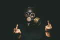 Man in gas mask shows middle fingers sign by both hands