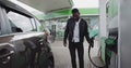 A Man Gets Out Of The Car At The Gas Station. Filling Benzine Gasoline Fuel In Car At Gas Station. African American Man