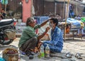 A man gets a shave at a street barber shop