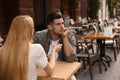 Man getting bored during date with overtalkative young woman at outdoor cafe Royalty Free Stock Photo