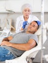 Man getting facial deep hydration procedure from experienced cosmetologist in aesthetic medicine clinic