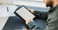 Man getting visa and reading application on tablet, passport on desk.