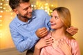 Man gifting necklace to delighted woman with glowing lights backdrop Royalty Free Stock Photo