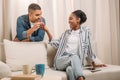 african american man gifting ring in heart shaped box to woman sitting on couch Royalty Free Stock Photo