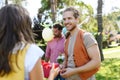 Man gifts a wrapped present to friend as surprise at birthday party. Friends reunite at garden party after a long time Royalty Free Stock Photo