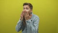 Man with ginger beard wearing denim jacket covers his mouth with both hands gesture in studio; surprise Royalty Free Stock Photo