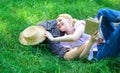 Man and girl lay on green grass having fun. Couple in love spend leisure reading book. Couple soulmates at romantic date