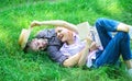 Man and girl lay on green grass having fun. Couple in love spend leisure reading book. Romantic couple students enjoy Royalty Free Stock Photo
