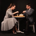 A man with a girl plays chess and smokes a pipe on a dark background