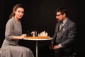 A man with a girl plays chess and smokes a pipe on a dark background